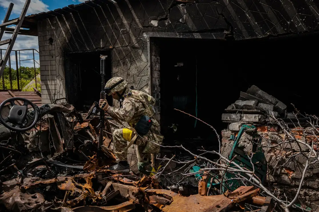 Un soldado de la unidad de fuerzas especiales ucranias ‘Kraken‘ pasa junto a los escombros en la aldea de Rus'ka Lozova, al norte de Jarkov, el 16 de mayo de 2022. Foto Afp