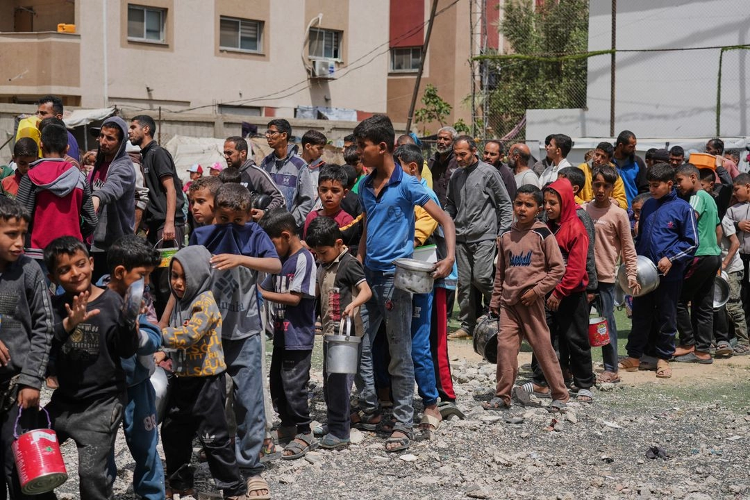 Palestinos esperan alimentos donados en un centro de distribución en Nuseirat, en el centro de la Franja de Gaza, el viernes 11 de abril de 2025.