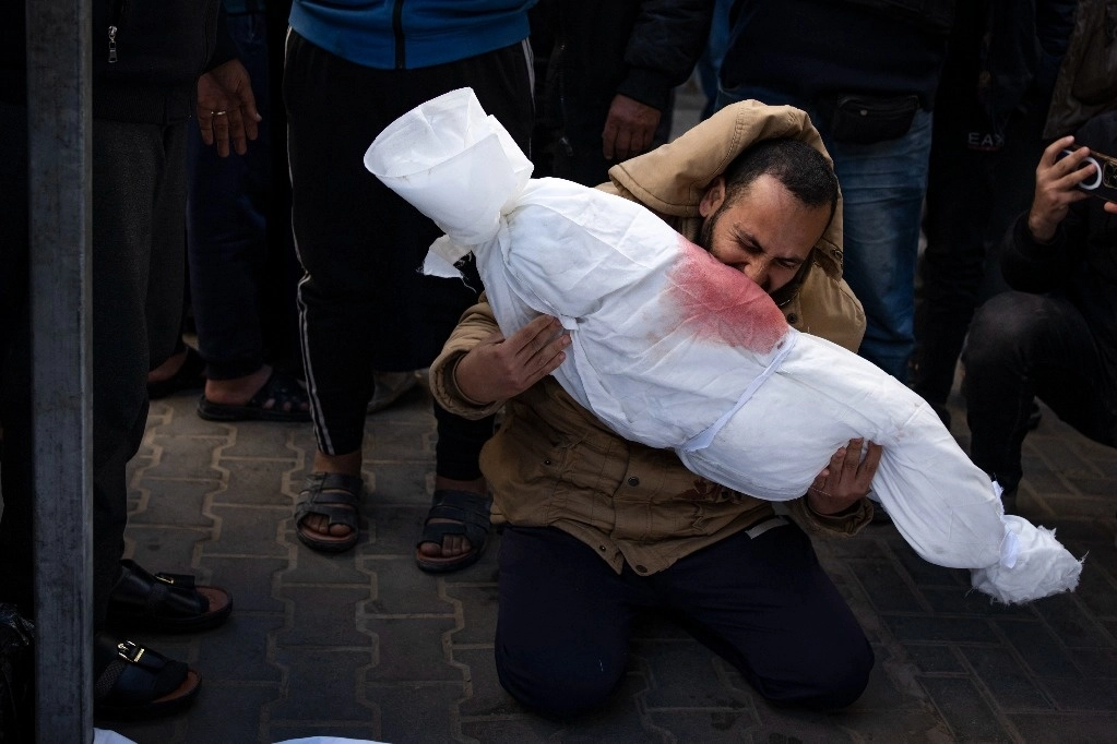 
Un hombre sostiene el cuerpo de su hija que murió en el bombardeo israelí de la Franja de Gaza, en la morgue de un hospital en Raf{a, el 21 de febrero de 2024. Foto Ap