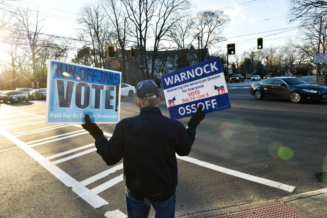 Un voluntario sostiene carteles durante las elecciones de segunda vuelta del Senado en Atlanta, Georgia. Foto Afp