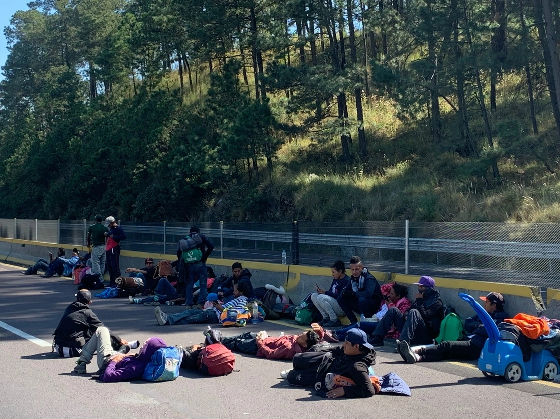 Integrantes de la caravana migrante descansan sobre la autopista México-Puebla, luego que fuera cerrada por la Guardia Nacional. Foto René Ramón