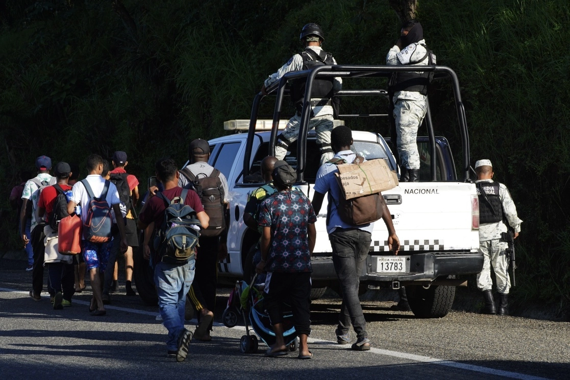Migrantes pasan junto a elementos de la Guardia Nacional mientras atraviesan una carretera costera en las afueras de Huixtla, Chiapas, el 25 de octubre de 2021. Foto Ap
