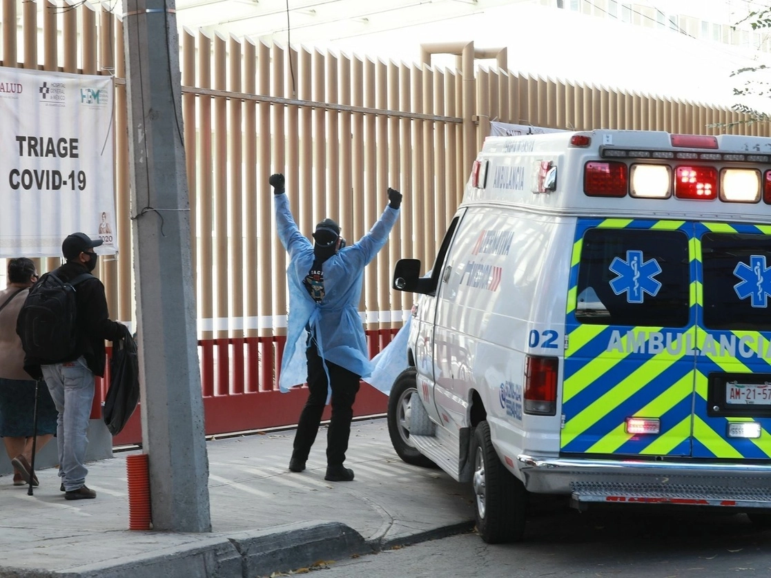 Un paramédico hace señas al personal del Hospital General de México para que la ambulancia, que traslada a un paciente con posibles síntomas de Covid-19, pueda ingresar al área de urgencias. Foto María Luisa Severiano