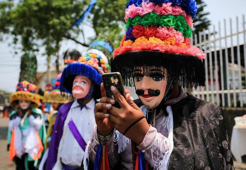 Un juerguista toma fotografías con su teléfono celular afuera de una iglesia durante las festividades de San Marcos en San Marcos, Nicaragua, el 24 de abril de 2023. Foto Afp