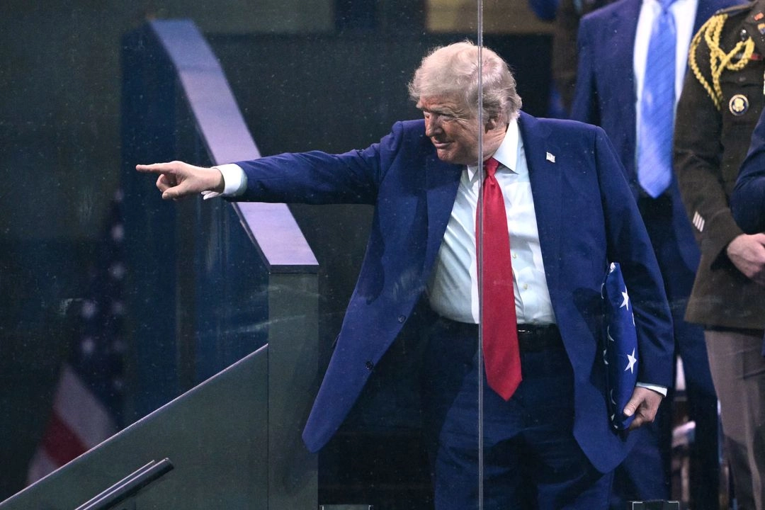 El presidente de Estados Unidos, Donald Trump, señala con la mano una bandera estadunidense que le regaló un miembro de los Caballeros Dorados del Ejército tras el Desfile del 250 Aniversario del Ejército en Washington, D. C., el 14 de junio de 2025. Foto 