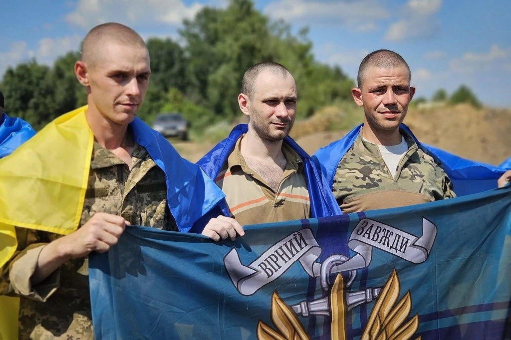 Prisioneros de guerra ucranianos sostienen la bandera de la Infantería de Marina mientras posan para una fotografía después de un intercambio de prisioneros en un lugar no revelado en Ucrania. Foto de Oficina de Prensa Presidencial de Ucrania vía AP 
