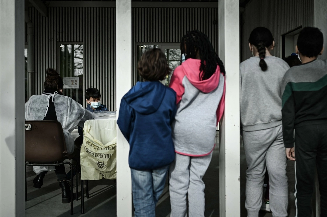En Francia, niños en edad escolar ven cómo le practican una prueba Covid-19 a uno de sus compañeros. Foto Afp