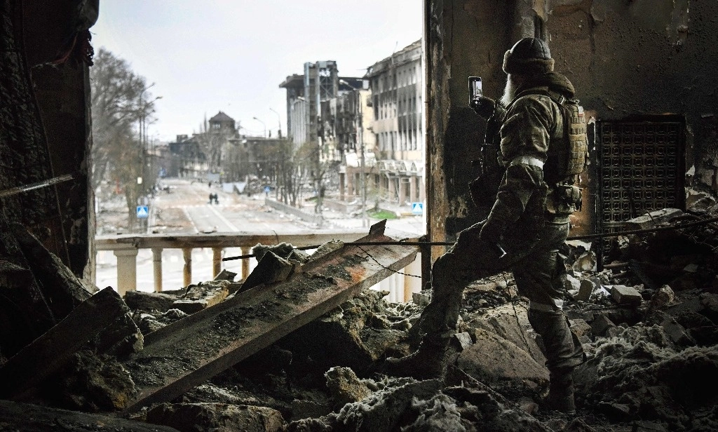 Un soldado ruso patrulla en el teatro de Mariúpol, bombardeado el 16 de marzo de 2022. Foto Afp