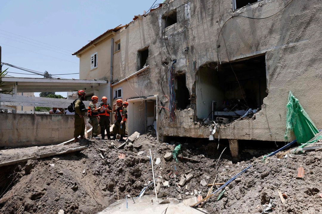 Soldados israelíes y socorristas verifican los daños causados ​​a un edificio por un ataque iraní en Beit She'an , en medio del continuo intercambio de disparos entre Irán e Israel, el 21 de junio de 2025. 