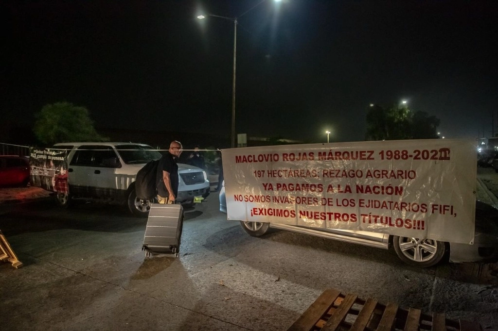 Posesionarios de terrenos bloquean la vía de acceso al Aeropuerto Internacional de Tijuana, por lo que los pasajeros han tenido que caminar varios kilómetros para poder tomar sus vuelos. Foto La Jornada Baja California