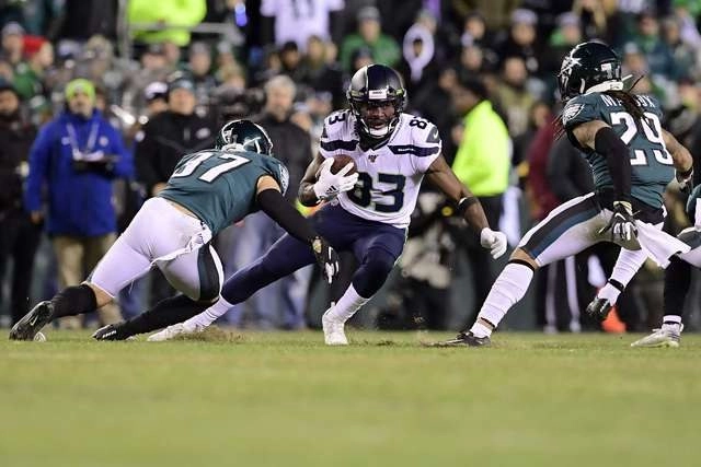 David Moore de los Halcones Marinos de Seattle lleva el balón  ante la mirada de los defensores de Filadelfia. Foto Afp
