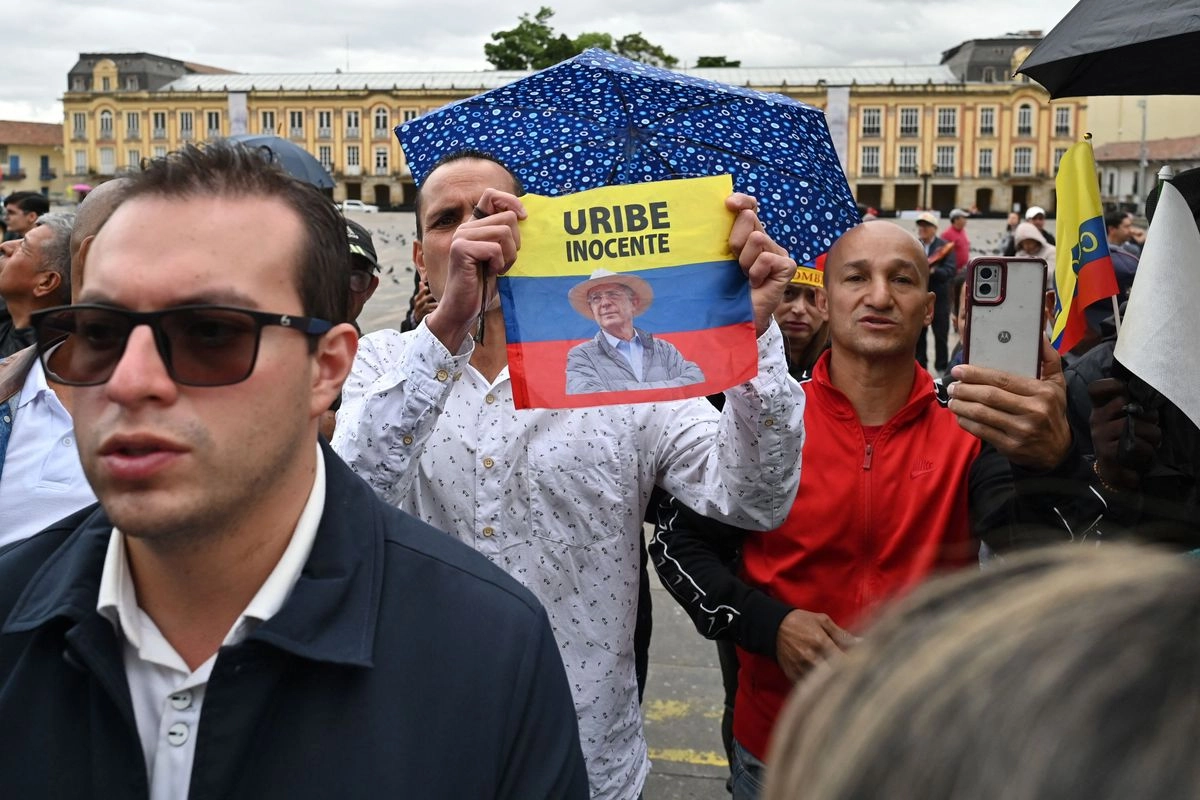 Un hombre muestra una bandera colombiana en señal de apoyo hacia el ex presidente Álvaro Uribe, mientras espera fuera de la catedral antes de la misa funeral por el fallecido aspirante presidencial y senador Miguel Uribe, en la Catedral Primada Metropolitana de Bogotá, el 13 de agosto de 2025. Foto