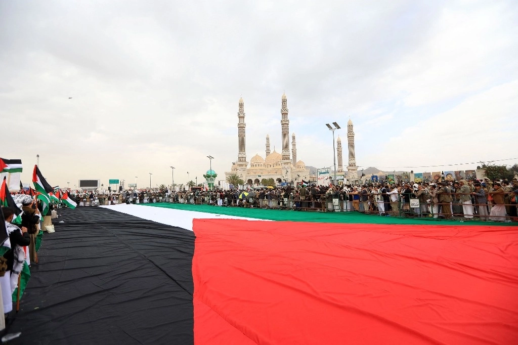 Pobladores de Yemen se reúnen frente a una bandera de palestina, en apoyo de la población palestina en Gaza. Foto Afp  