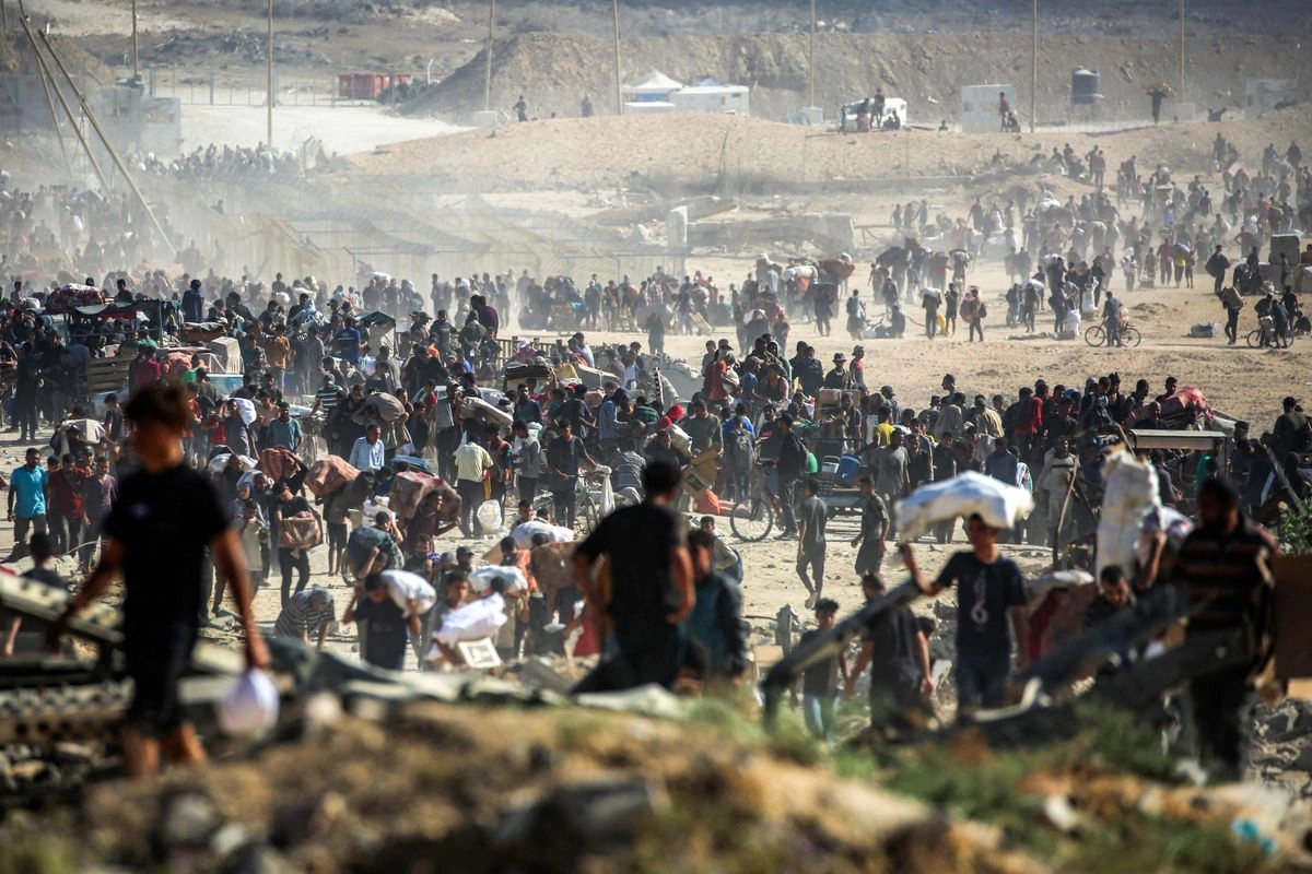 Personas caminan con paquetes de ayuda humanitaria recibidos de un centro de distribución gestionado por la Fundación Humanitaria de Gaza (FGH), respaldada por Estados Unidos e Israel, en el llamado "corredor Netzarim", en Nuseirat, en el centro de la Franja de Gaza, el 30 de septiembre de 2025. 