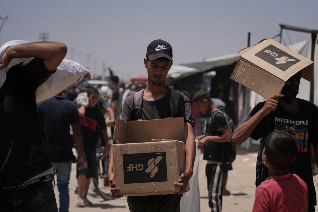 Palestinos llevan bolsas y cajas con alimentos y paquetes de ayuda humanitaria entregados por la Fundación Humanitaria de Gaza, una organización respaldada por Estados Unidos, en Rafah, al sur de la Franja de Gaza, el lunes 16 de junio de 2025. Foto 