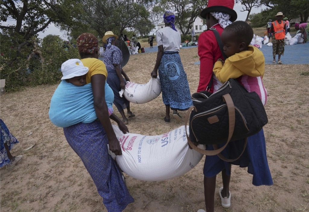 Zanyiwe Ncube, a la izquierda, lleva una bolsa de sorgo durante una distribución de alimentos en el distrito de Mangwe, en el suroeste de Zimbabwe, el viernes 22 de marzo de 2024. Una nueva sequía ha dejado a millones de personas enfrentando hambre en el sur de África mientras experimentan los efectos del clima extremo que los científicos decir, es cada vez más frecuente y más perjudicial. Foto Ap 