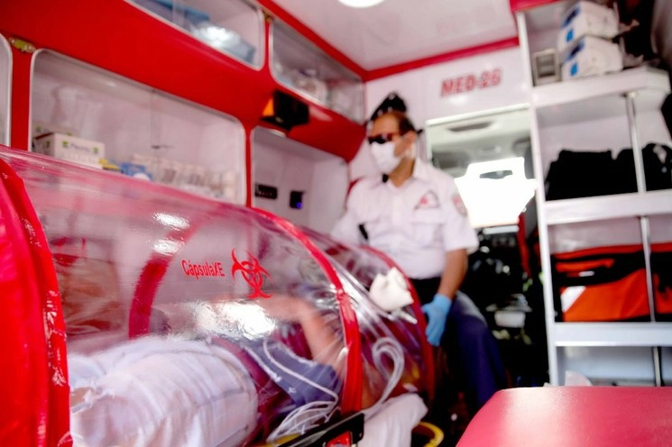 Un paramédico vigila a una persona trasladada en una cápsula plástica sellada y flexible para el tratamiento de COVID-19. Foto Xinhua