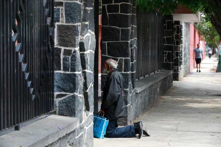 Un hombre de la tercera edad reza afuera de una iglesia cerrada por la contingencia de Covid-19, en la alcaldía Iztapalapa. Foto Alfredo Domínguez / archivo