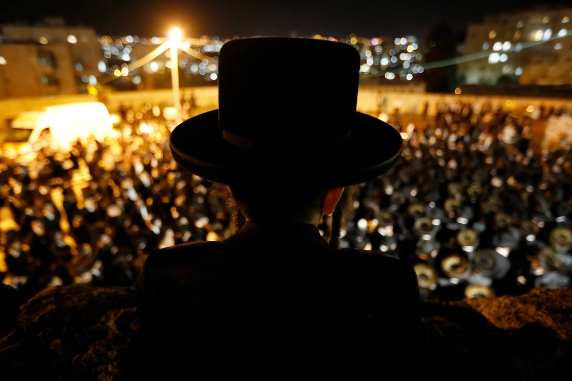 Un joven israelí observa los funerales por la estampida en  el Monte Meron. Foto Ap