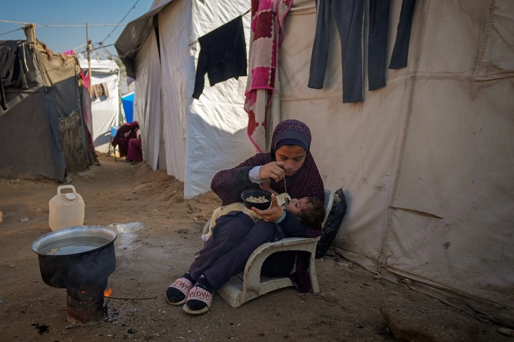 Una menor de 16 años alimenta a su hermana en un campamento para palestinos desplazados en Deir al-Balah, en la franja de Gaza, el 1° de diciembre de 2024. Foto Ap