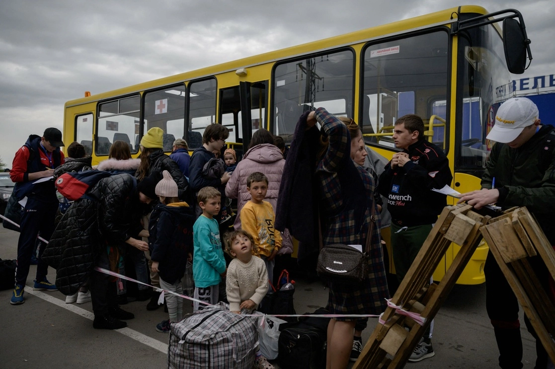 Familias de territorios ocupados por Rusia en Ucania llegan en un convoy humanitario a un centro de registro y procesamiento para desplazados internos en Zaporriyia en medio de la invasión rusa, el 29 de abril de 2022. Foto Afp 