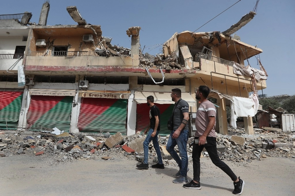 Los aldeanos libaneses pasan por un edificio que fue destruido por los bombardeos israelíes, en Kfar Kila, una aldea fronteriza libanesa con Israel, al sur del Líbano, el 18 de abril de 2024. Foto Ap 