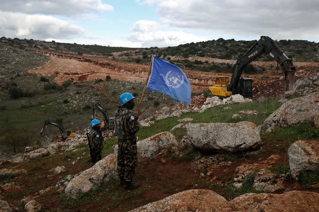 Las fuerzas de paz de la ONU sostienen su bandera mientras observan que las excavadoras israelíes intentan destruir túneles construidos por Hezbollah, cerca de la aldea fronteriza entre el Líbano e Israel de Mays al-Jabal, Líbano, el 13 de diciembre de 2019. Foto Ap
