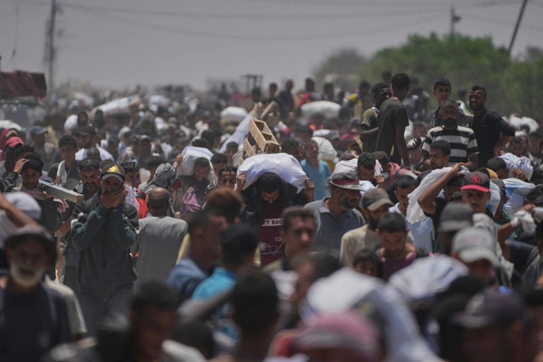 Palestinos llevan bolsas con alimentos y paquetes de ayuda humanitaria entregados por la Fundación Humanitaria de Gaza, una organización respaldada por Estados Unidos, en Rafah, al sur de la Franja de Gaza, el lunes 9 de junio de 2025. Foto 