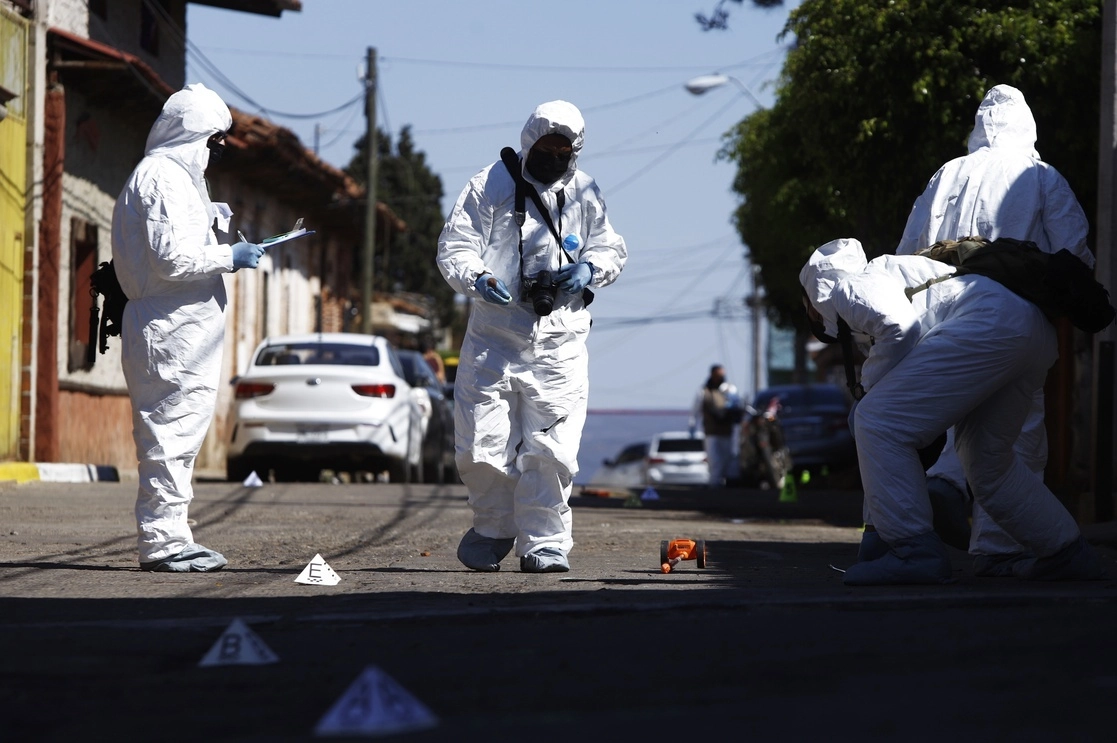 Peritos de la fiscalía de Michoacán revisan las inmediaciones del domicilio donde supuestamente habrían sido ejecutadas 17 personas por presuntos integrantes del crimen organizado la tarde del domingo pasado en la calle Reforma del poblado de San José de Gracia. Foto Ap