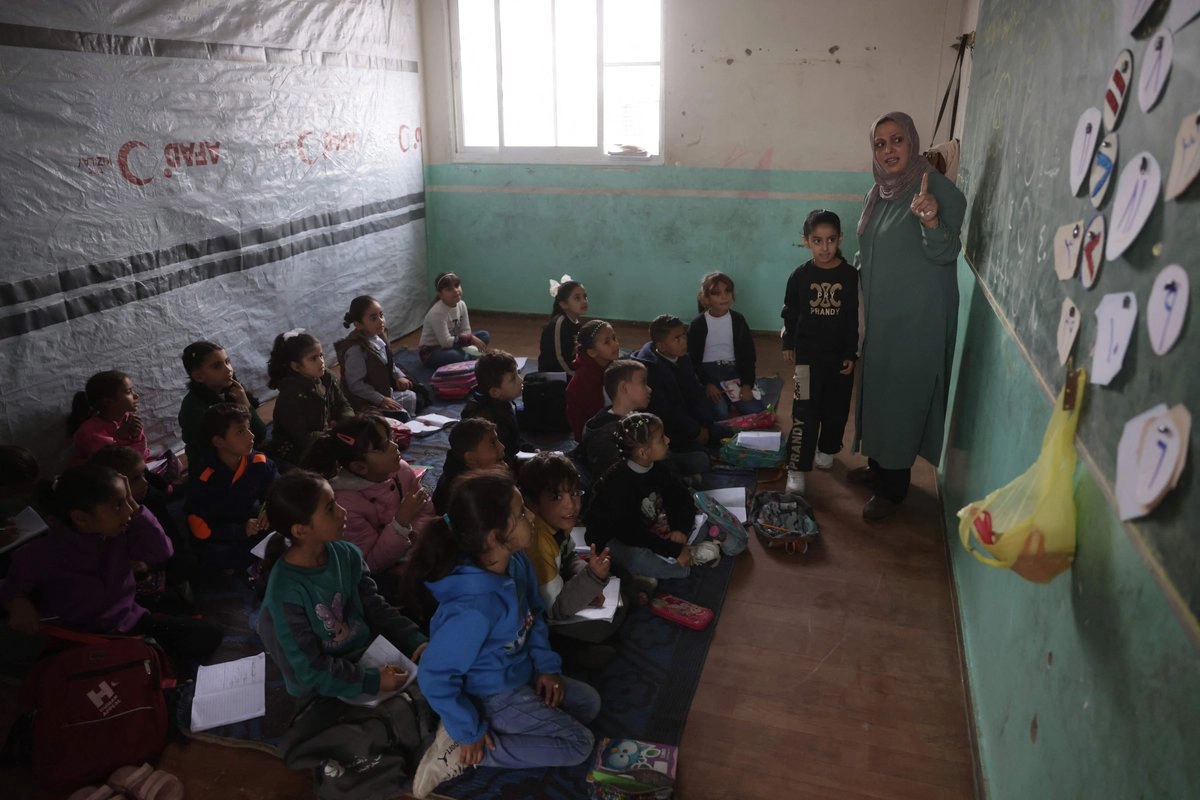 Niños palestinos toman clase en una escuela en Deir al Balah, Gaza, donde viven con sus familias desplazadas