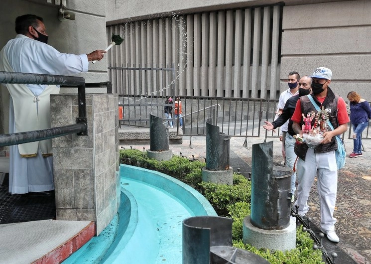 Un sacerdote bendice -manteniendo sana distancia- a los feligreses en la explanada de la Basílica de Guadalupe, ayer 6 de septiembre 2020. Foto Marco Peláez 