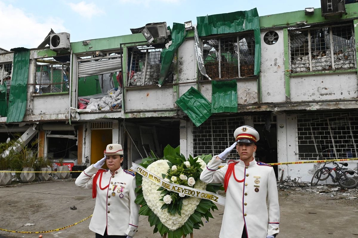 Miembros de la Escuela Militar de Colombia saludan junto a una corona de flores colocada frente al lugar donde explotó una bomba en Cali, Colombia.