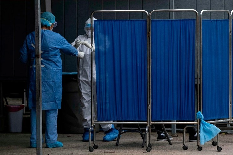 Personal de salud maneja una muestra mientras realiza una prueba para COVID-19 detrás de un biombo médico, en el Hospital General en Tijuana. Foto AFP 