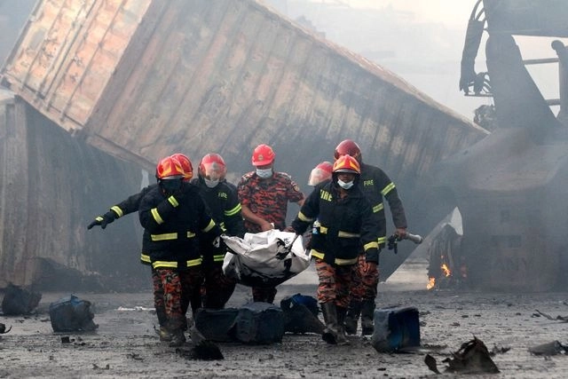 Bomberos trasladan el cadáver de una víctimas del incendio en el depósito de contenedores en Chittagong, Bangladesh. Foto Afp