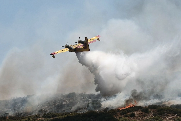 Una aeronave libera líquido para intentar sofocar un incendio en la ciudad de Volos, Grecia, el 27 de julio de 2023. Foto Afp 