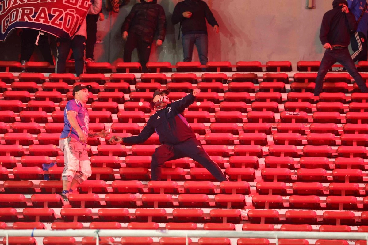  Un hincha de la Universidad de Chile se prepara para lanzar una piedra durante la interrupción del partido de vuelta de los octavos de final de la Copa Sudamericana entre Independiente de Argentina y Universidad de Chile en el estadio Libertadores de América en Avellaneda, provincia de Buenos Aires, Argentina, el 20 de agosto de 2025. Foto