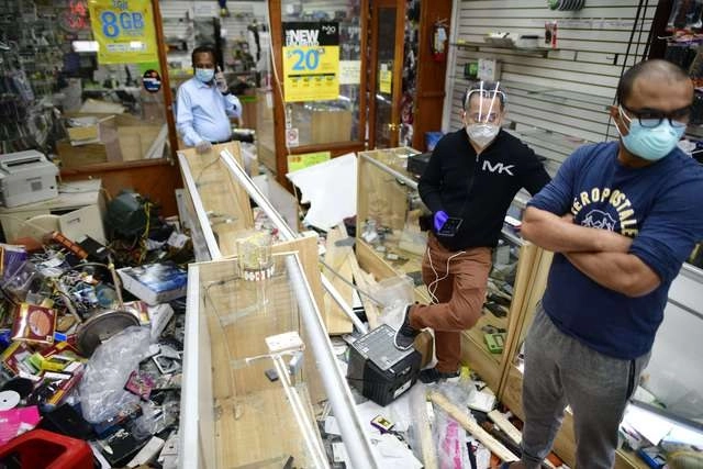 Dueños de comercios limpian los destrozos después de las protestas de anoche contra la muerte de George Floyd. Foto Afp 
