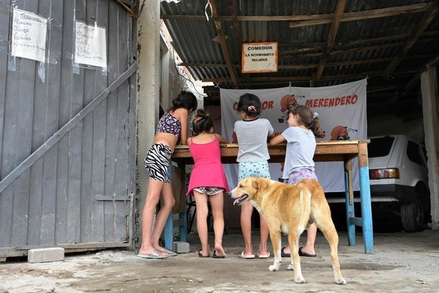 Niños esperan recibir sus recipientes de plástico con comida gratis en el comedor social "Las Hormiguitas Viajeras" en Loma Hermosa, provincia de Buenos Aires. Foto Afp