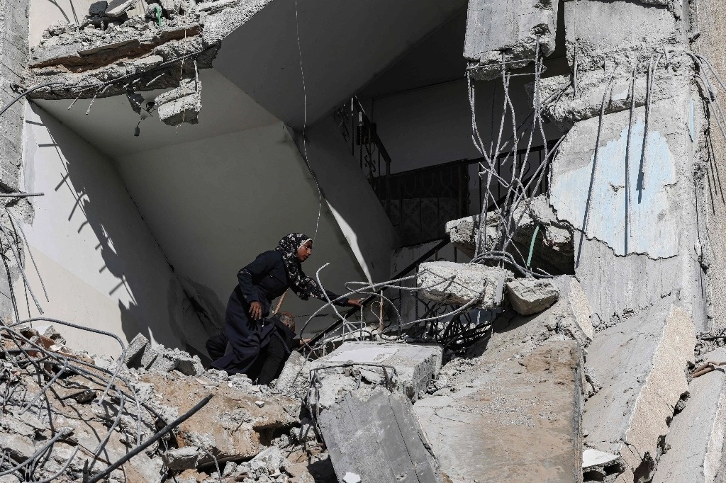 Una mujer palestina busca entre los escombros de la mayor torre residencial de Rafah, que fue blanco de un ataque aéreo israelí nocturno en el sur de la franja de Gaza, mientras continúan los enfrentamientos entre Israel y el grupo armado islamita Hamas. Foto Afp