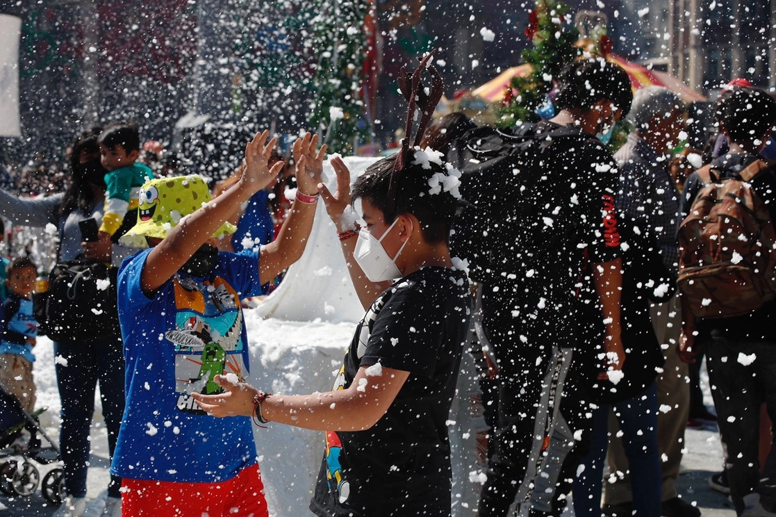 Adultos, jóvenes y niños juegan en la nieve artificial y en el tobogán de hielo, parte de las atracciones de la feria navideña inaugurada ayer en el Zócalo capitalino. Foto Cristina Rodríguez