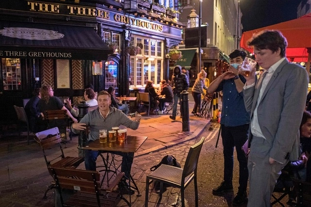 Clientes beben en un ‘pub’ en Londres, Inglaterra, durante el primer día de horario restringido como medida contra la pandemia. Foto Afp 