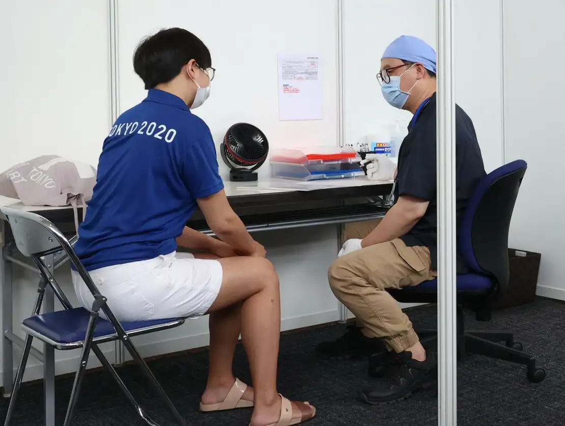 Una mujer es entrevistada por un médico antes de recibir una vacuna contra el Covid-19 en la oficina del Gobierno Metropolitano de Tokio durante el inicio de la campaña de inmunización a las personas involucradas en los Juegos Olímpicos de Tokio 2020, el 18 de junio de 2021. Foto Afp