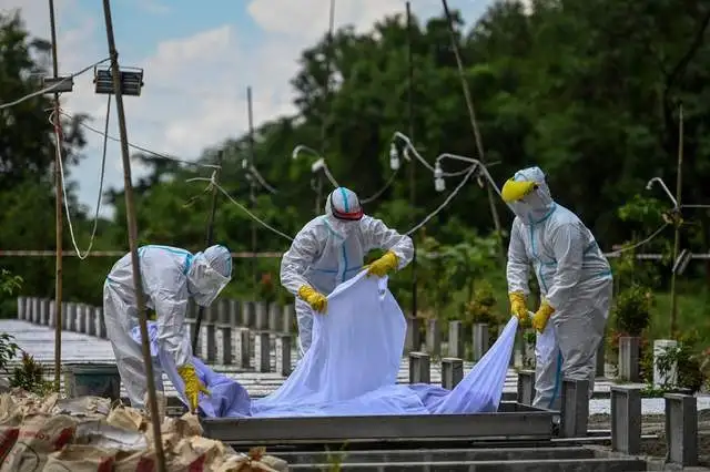 Voluntarios con equipo de protección entierran a una víctima de coronavirus en un cementerio de Rangún, Birmania. Foto Afp 