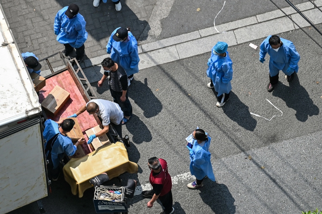 Trabajadores descargan cajas con víveres en el distrito Jing'an en Shanghai, el 16 de mayo de 2022. Foto Afp