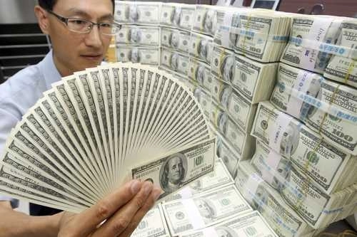 Un empleado bancario muestra dólares en una sucursal de Corea del Sur. Foto Ap/ archivo