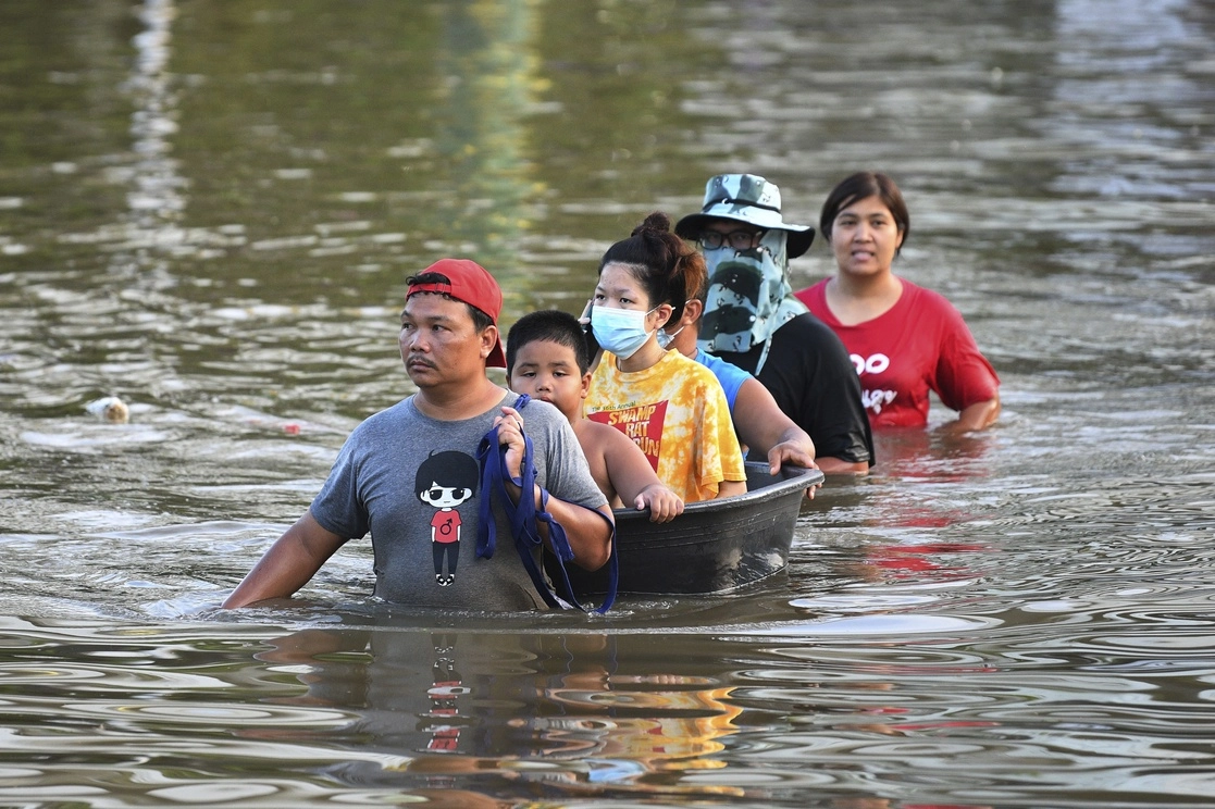 Tailandeses avanzan por una calle inundada en la provincia de Chaiyaphum, al noreste de Bangkok, el 28 de septiembre de 2021. Foto Ap 