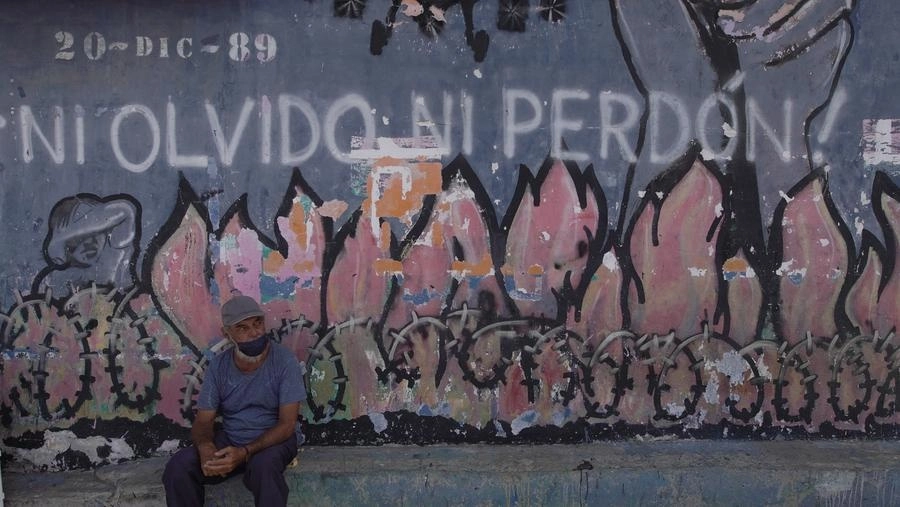 Un residente descansa frente a un mural alusivo a la invasión de EU a Panamá de 1989 en el barrio de El Chorrillo, uno de los principales puntos destruidos durante la invasión, en la Ciudad de Panamá, el 25 de marzo de 2022. Foto Xinhua