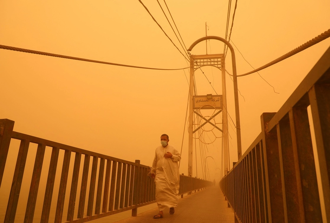 Un hombre atraviesa un puente peatonal sobre el río Éufrates, durante una fuerte tormenta de arena en Nasiriyah, Irak, el 23 de mayo de 2022. Foto Afp 