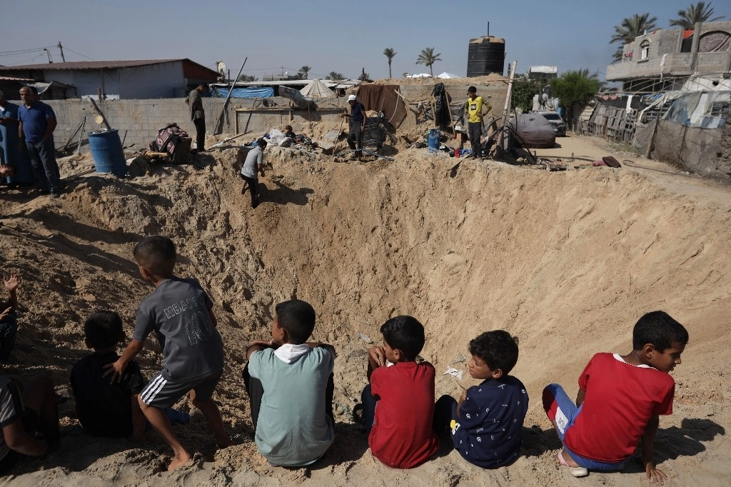Uno de los cráteres causados la víspera por las bombas israelíes en la localidad de Jan Yunis, Gaza. Foto Ap