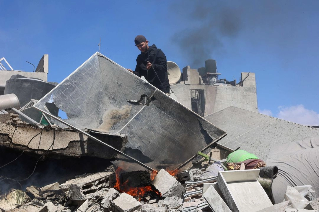 Palestino camina sobre los escombros dejados por un ataque israelí en el barrio de Al-Sabra, en la franja de Gaza, el 19 de marzo de 2025. Foto 